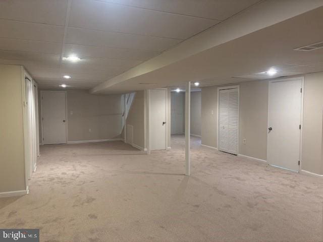 finished basement featuring light carpet, visible vents, and baseboards