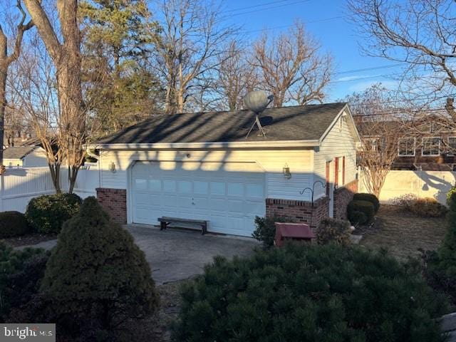 view of home's exterior featuring brick siding, a detached garage, and fence