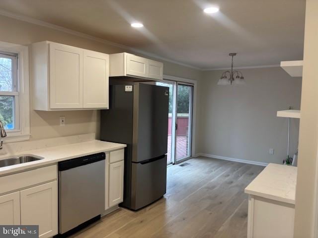 kitchen featuring appliances with stainless steel finishes, white cabinetry, a sink, and ornamental molding