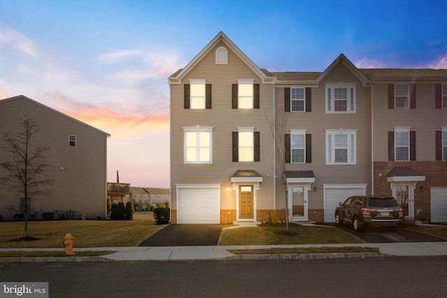 townhome / multi-family property featuring a garage, driveway, and brick siding