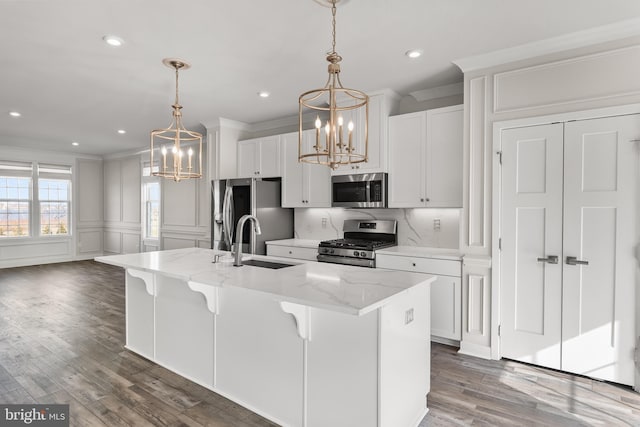 kitchen with white cabinetry, a kitchen island with sink, stainless steel appliances, and light stone counters