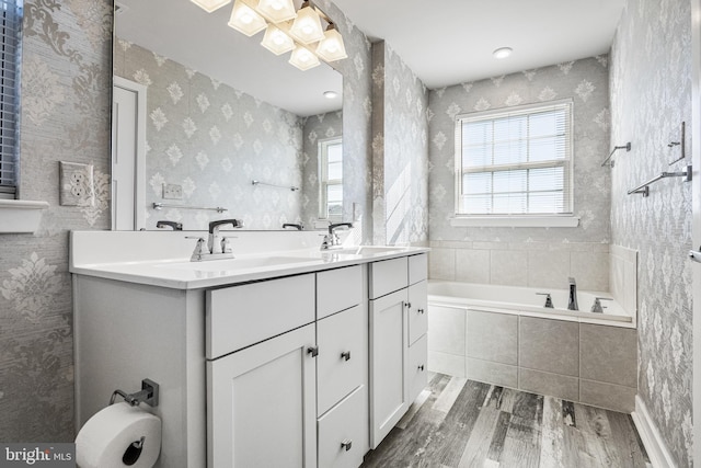 bathroom with vanity, tiled tub, a wealth of natural light, and wood-type flooring