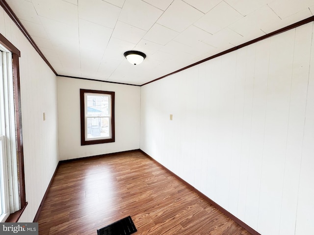 spare room with ornamental molding, visible vents, and wood finished floors