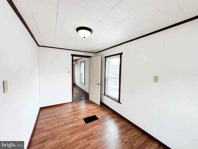 spare room with ornamental molding and wood finished floors