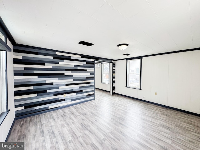 empty room with light wood-style floors and crown molding