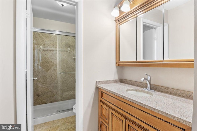 bathroom featuring vanity, a shower stall, and toilet