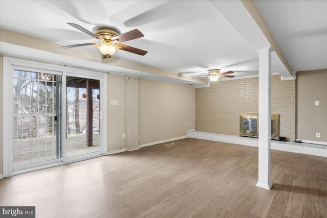 unfurnished living room with light wood-style floors, brick wall, and baseboards