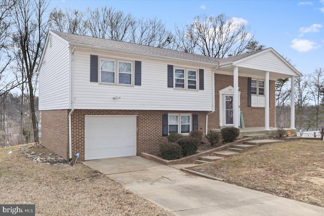 bi-level home with an attached garage, concrete driveway, and brick siding