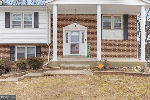 entrance to property featuring covered porch and brick siding