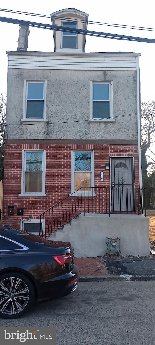 view of front of property featuring brick siding and stucco siding