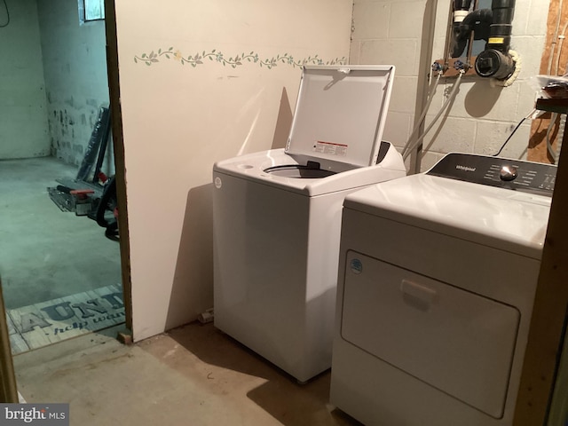 washroom with laundry area, washer and clothes dryer, and concrete block wall