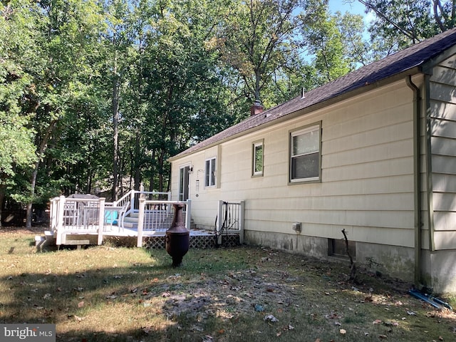 view of side of home featuring a lawn, a wooden deck, and a chimney