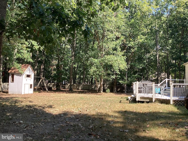 view of yard with a deck, a shed, an outdoor structure, and a fenced backyard