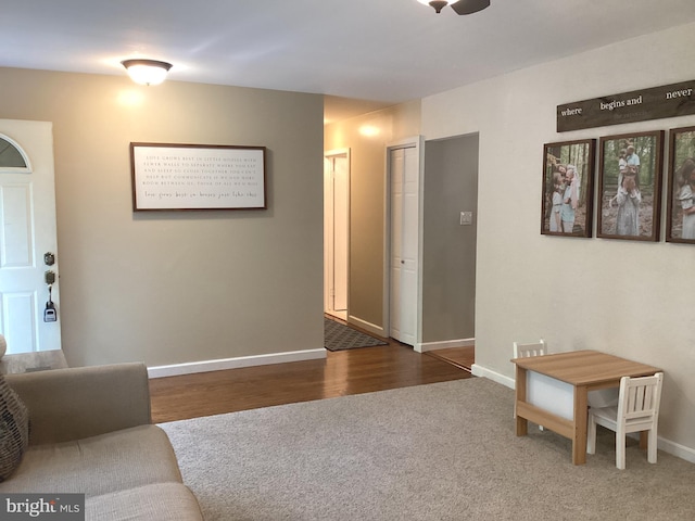 living area with baseboards, dark wood-style flooring, and dark carpet