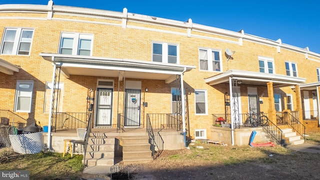 multi unit property featuring covered porch and brick siding