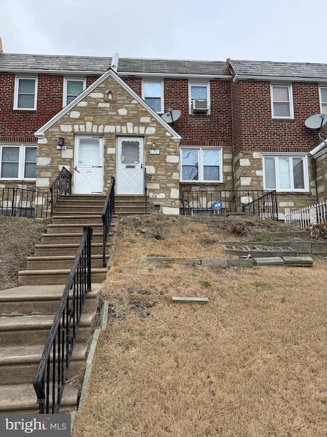 view of property featuring entry steps, stone siding, and brick siding