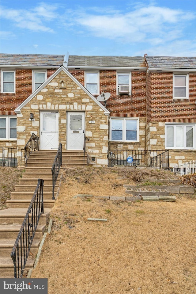 townhome / multi-family property with entry steps, stone siding, and brick siding