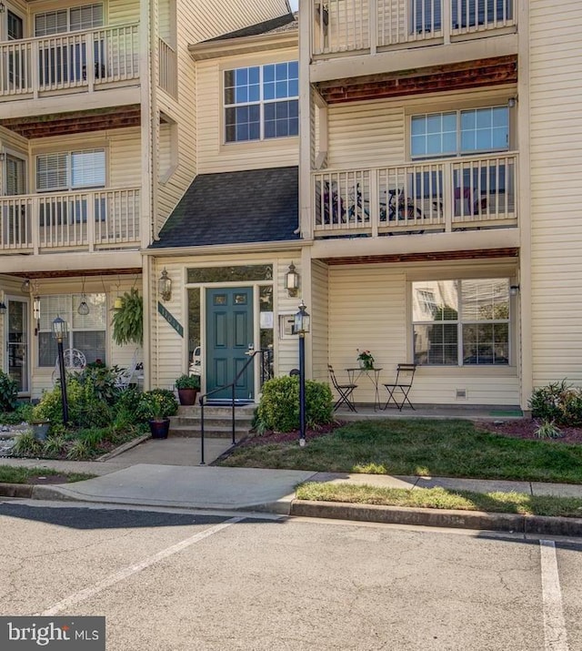 exterior space featuring uncovered parking and a shingled roof