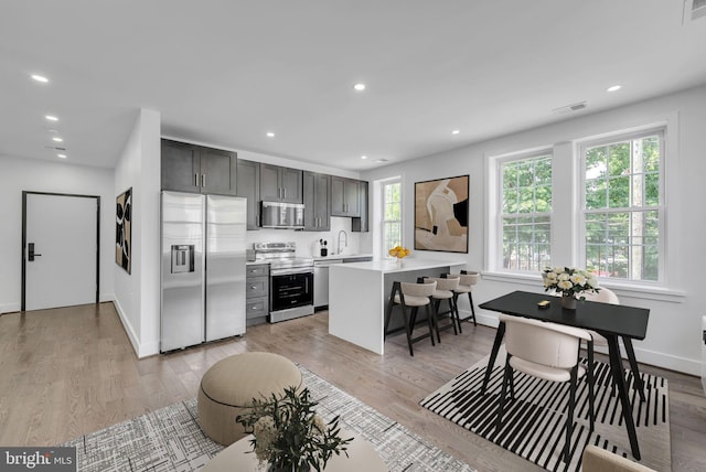 kitchen featuring light wood-type flooring, stainless steel appliances, a breakfast bar, a kitchen island, and sink