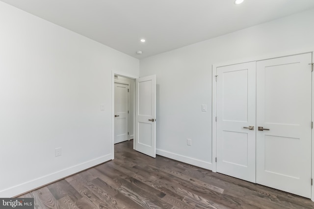 unfurnished bedroom featuring dark wood-type flooring and a closet