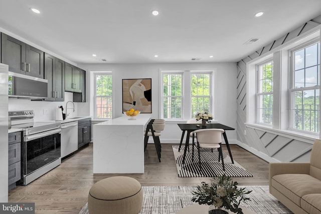 kitchen with stainless steel appliances, a sink, visible vents, light countertops, and light wood-type flooring