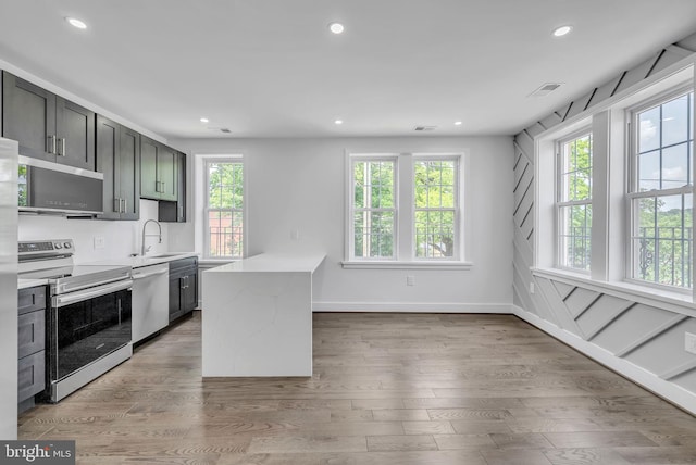 kitchen featuring sink, appliances with stainless steel finishes, light stone countertops, and wood-type flooring