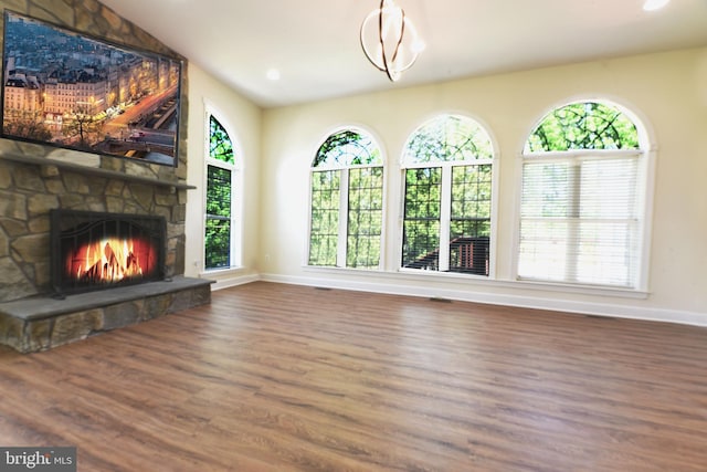 unfurnished living room with dark wood-type flooring and a stone fireplace