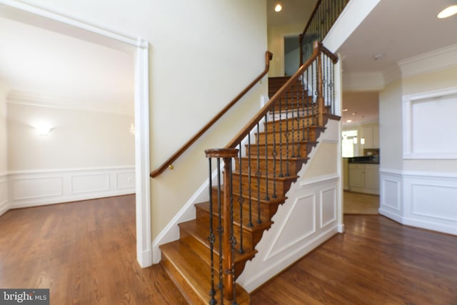 stairs featuring hardwood / wood-style floors and ornamental molding