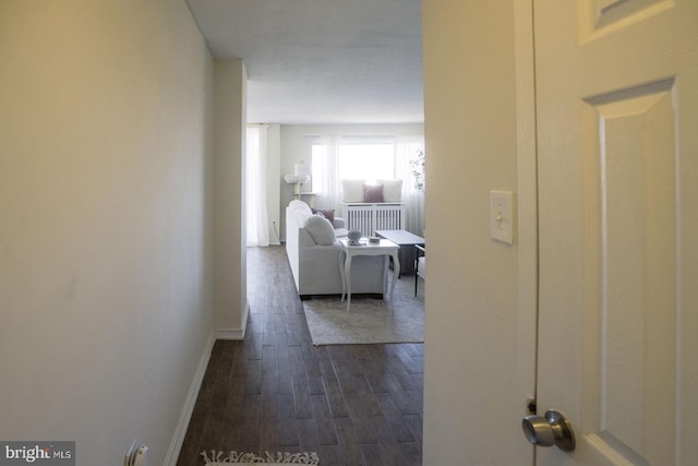 hall with radiator, dark wood-type flooring, and baseboards