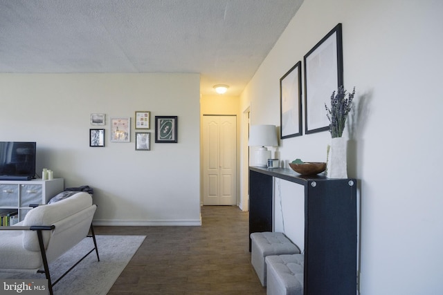 living room featuring baseboards, dark wood-type flooring, and a textured ceiling