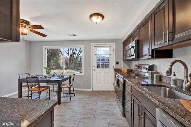 kitchen featuring stainless steel appliances, a sink, visible vents, dark brown cabinets, and dark stone counters