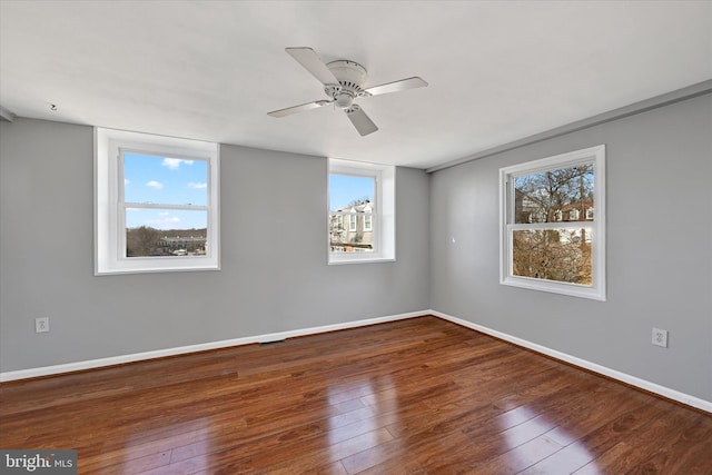 spare room with a ceiling fan, dark wood-style flooring, and baseboards