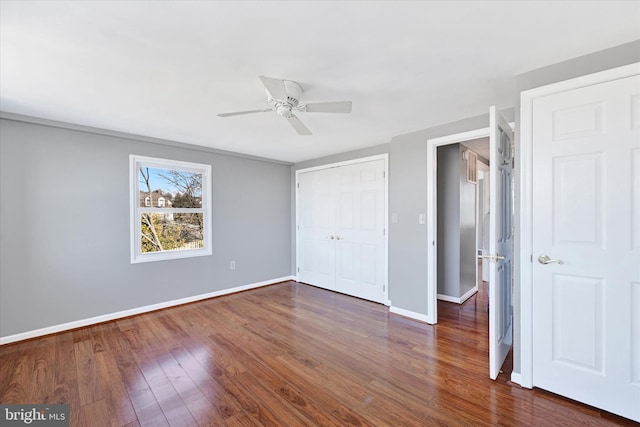 unfurnished bedroom featuring ceiling fan, a closet, baseboards, and dark wood-type flooring