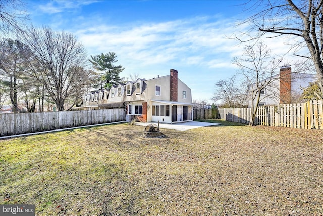 rear view of property with a sunroom, a patio area, a fenced backyard, and a gambrel roof