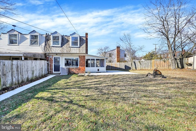 back of property featuring a sunroom, a fenced backyard, a yard, central air condition unit, and brick siding