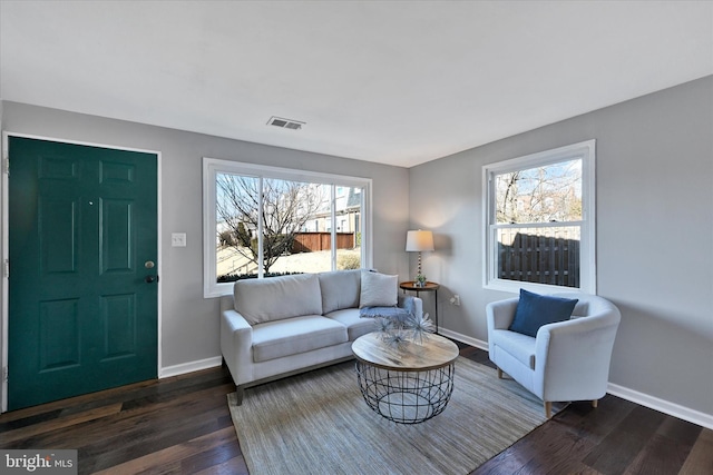 living room with baseboards, visible vents, and dark wood finished floors