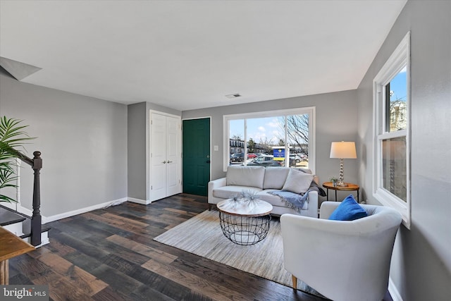 living room featuring dark wood-style flooring, visible vents, and baseboards