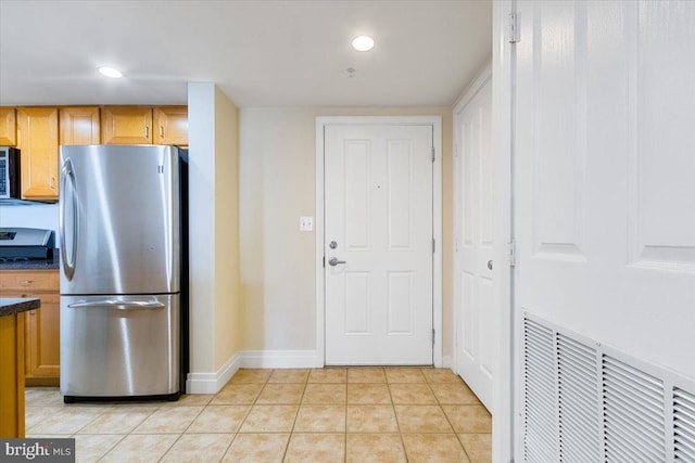 kitchen with light tile patterned floors, dark countertops, recessed lighting, visible vents, and freestanding refrigerator