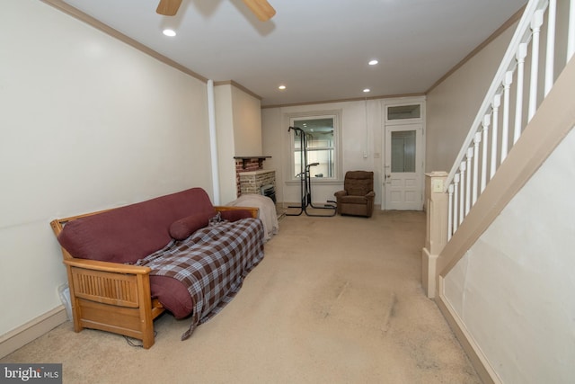 sitting room featuring a fireplace, ceiling fan, crown molding, and light colored carpet