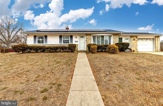 single story home featuring a front lawn, a garage, and solar panels