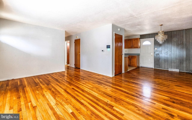 unfurnished living room featuring a chandelier and dark hardwood / wood-style floors