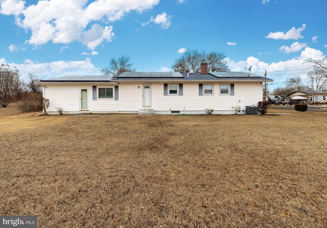 single story home featuring central air condition unit, solar panels, and a front yard