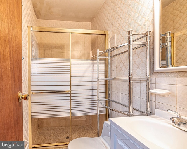 bathroom featuring tile walls, toilet, vanity, and a shower with shower door