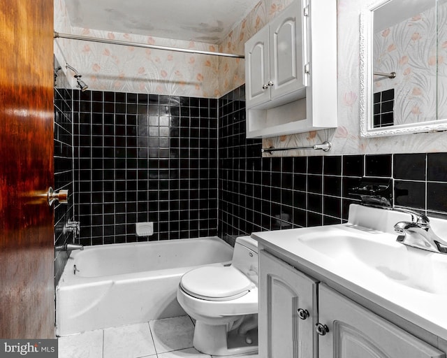 full bathroom featuring tiled shower / bath, toilet, tile walls, tile patterned floors, and vanity