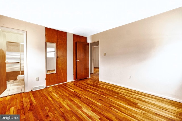 unfurnished bedroom featuring hardwood / wood-style floors and ensuite bathroom