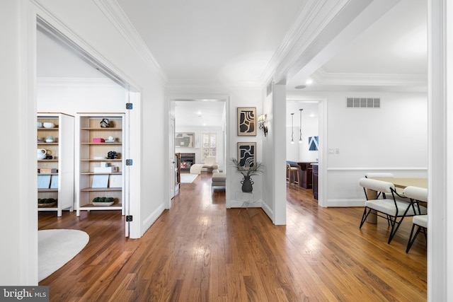 entrance foyer featuring a lit fireplace, visible vents, wood-type flooring, and crown molding