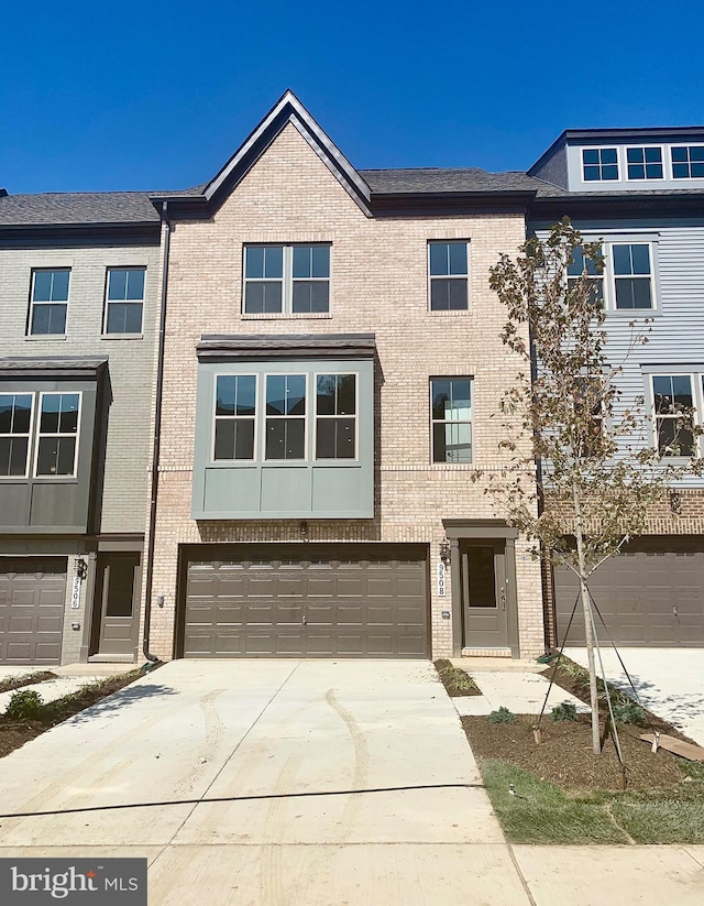 townhome / multi-family property featuring a garage, concrete driveway, and brick siding