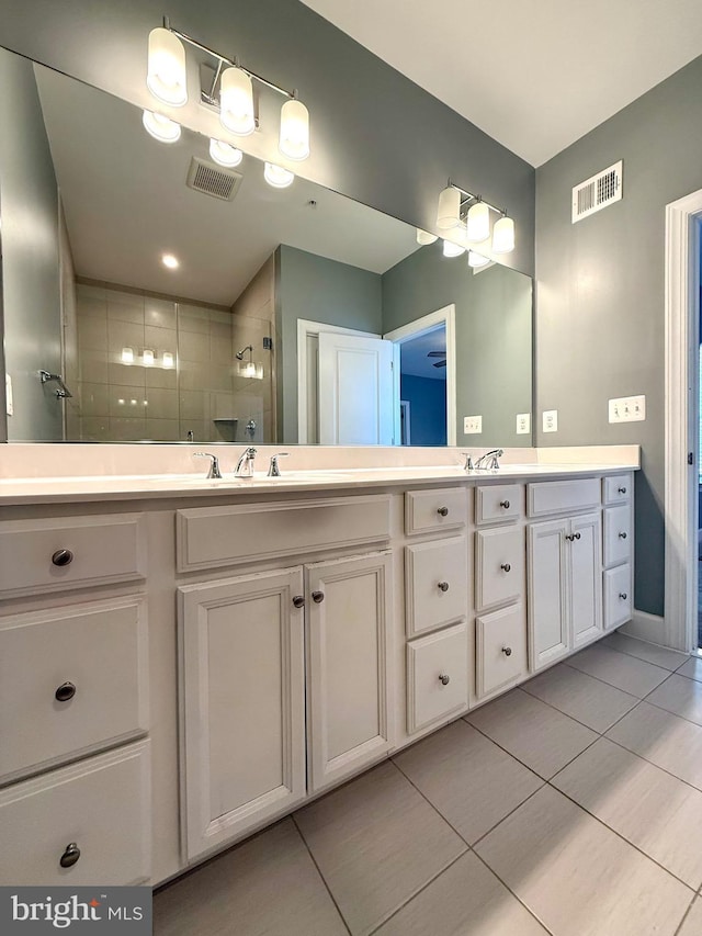 full bath featuring tile patterned floors, double vanity, visible vents, and a tile shower