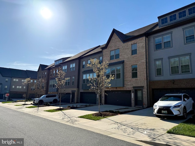 exterior space with brick siding, an attached garage, a residential view, and driveway