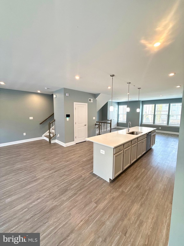 kitchen with baseboards, a sink, open floor plan, recessed lighting, and wood finished floors